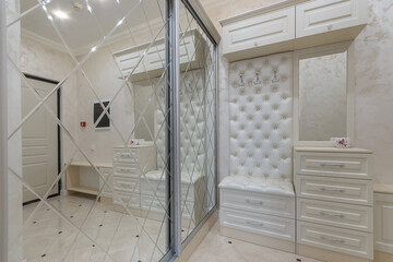 Magnificent design of the entrance hall with white furniture and a built-in wardrobe with sliding mirrored doors.