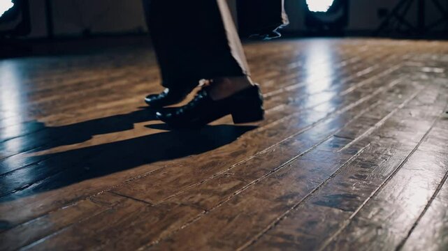 Slow-motion close-up of a tap dancer&rsquo;s feet performing rhythmic footwork on a dimly lit wooden floor