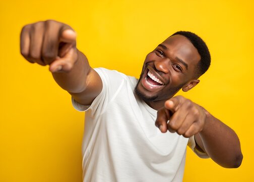 Cheerful African American man pointing at camera on yellow background