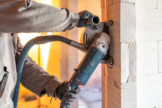 Construction worker cutting aerated concrete block wall using circular saw with vacuum dust extraction