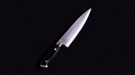 Sharp chef's knife with black handle isolated on black background.