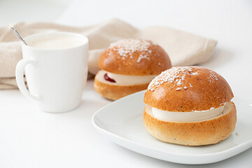 Two traditional Finish sweet buns with whipped cream for Shrove Tuesday. Laskiaispulla. A white cup with coffee.