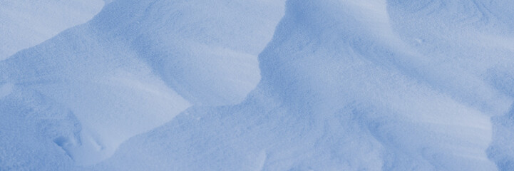 Obraz premium Beautiful winter background with snowy ground. Natural snow texture. Wind sculpted patterns on snow surface. Wide panoramic texture for background and design.