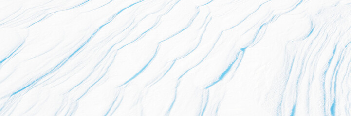 Wide panoramic winter background with snowy ground. Natural snow texture. Wind sculpted patterns on snow surface. Arctic, Polar region.