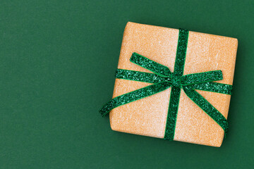 Gift box with glittering ribbon on a green background. Festive layout with place for text.