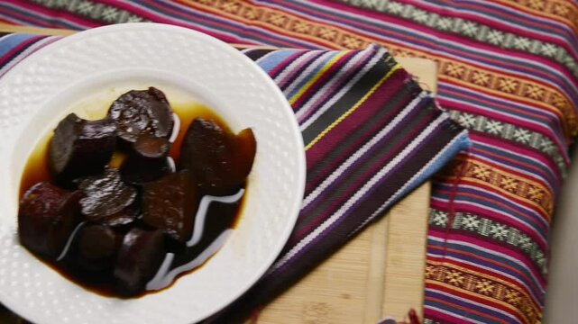 A video showcasing dulce de camote (sweet potato candy), a traditional Salvadoran dessert, on a wooden board with sauce and Central American fabric decor.