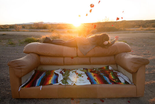 Woman lying on couch throwing rose petals