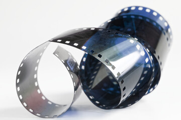 Curled 35mm film negative with a blue tint on a white background. A conceptual image representing...
