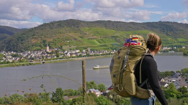 Side view of solo female hiker with backpack walking in slow motion on a trail in the Rhine River Valley on a sunny autumn day, Germany