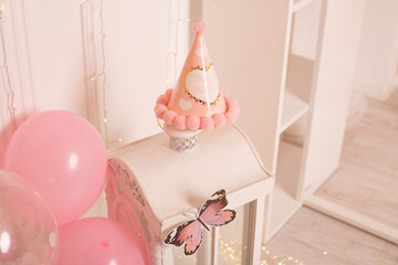 A delicate white and pink party setup with a festive hat, perfect for a first birthday celebration.