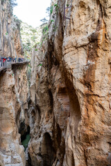 Hikers on El Caminito del Rey trail experience the stunning views of the gorge and cliffs in Spain.