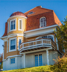 Obraz premium Facade of a yellow wooden house with creative architectural solutions.