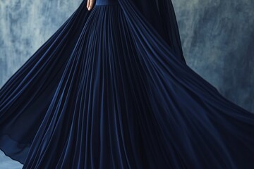 Naklejka premium Elegant flowing blue gown with pleated skirt in motion against textured backdrop