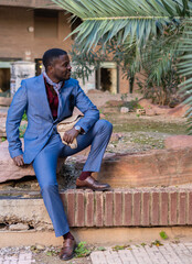 Obraz premium A Stylish Man in a Tailored Suit Poses at an Outdoor Location Surrounded by Nature