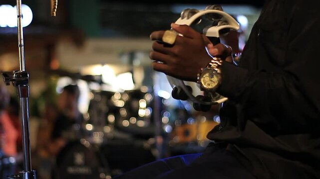 man playing half-moon tambourine in concert