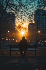 Fototapeta premium Silhouette of Person on Bench at Sunset