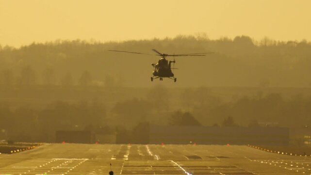 Military helicopter landing at sunset from the airbase runway