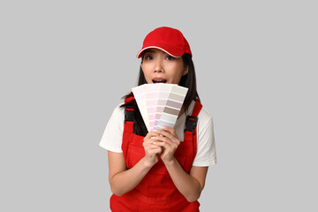 Female Asian shocked painter with paint color palettes on grey background