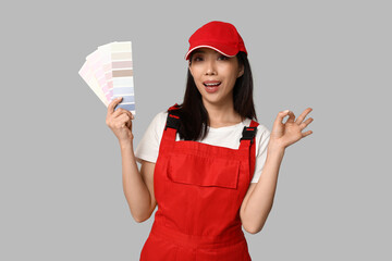 Female Asian painter with paint color palettes showing OK gesture on grey background
