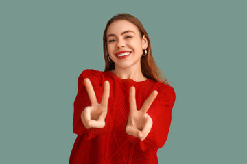 Pretty young woman showing peace gestures on blue background