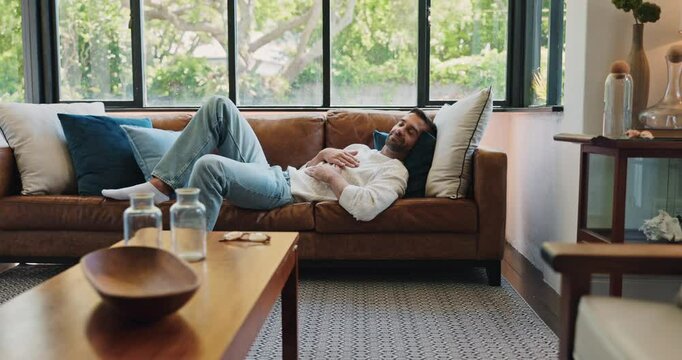 Man, relax and chilling on weekend in home, happy and listening to music in living room. Comfortable, couch and person for lazy resting in modern apartment, dancing and hearing sound on morning