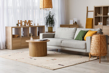 Interior of cozy living room with grey sofa, wooden table and lamps