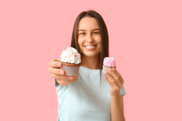 Young woman with sweet cupcakes on pink background. Valentine's Day celebration