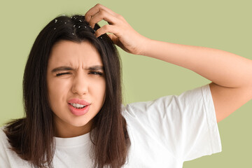 Fototapeta premium Young woman with dandruff problem scratching head on green background