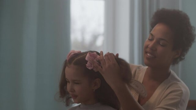 Smiling black woman tying daughter hair with scrunchie