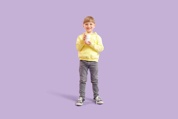 Little boy with glass of milk on lilac background