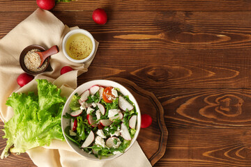 Composition with bowl of tasty salad and ingredients on wooden background