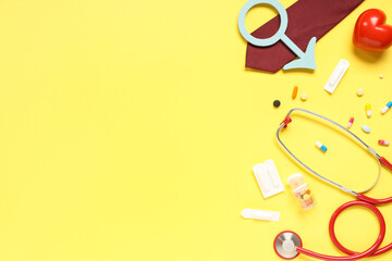Obraz premium Stethoscope, tie, heart, pills and male sign on yellow background. Prostate cancer awareness