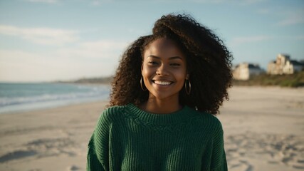 Good-looking young african gal in green themed sweater on a beach smiling