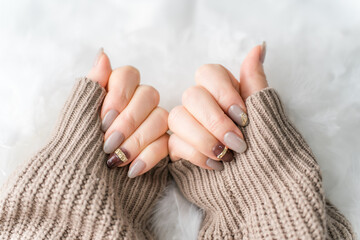 ネイルサロン・ジェルネイルをする女性（ベージュ・ブラウン・秋冬デザイン）
