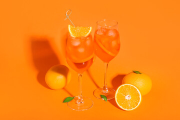 Glasses of Aperol spritz cocktail and fruits on orange background