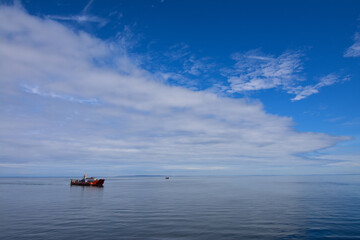 Ferry on the calm waters of Reloncavi Fjord in southern Chile (Patagonia) with blue sky and clouds. 