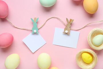 Composition with Easter eggs, thread and blank paper sheets on pink background