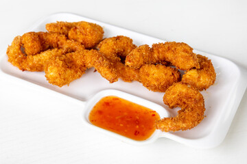 Thai style deep fried shrimp tempura on white plate with sweet chili sauce on white background. Seafood tempura dish of traditional Asian cuisine. Famous Thai appetizer.