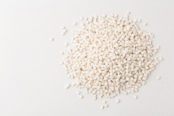 Pile of plastic granules on white background, top view. Space for text