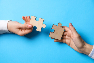 Business strategy and teamwork concept. Partners putting puzzle pieces together on light blue...