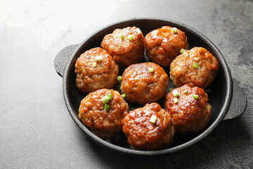 Tasty meatballs with green onion in baking dish on grey table, closeup