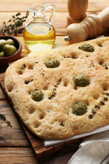 Delicious focaccia bread with olives, salt and thyme on wooden table, closeup