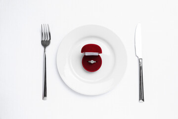 Beautiful engagement ring and setting for romantic dinner on white background, top view