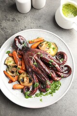 Roasted octopus served with vegetables and mushrooms on grey table, flat lay