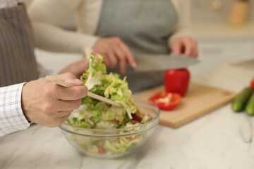 Senior couple cooking together at table in kitchen, closeup