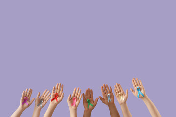 Many hands with different ribbons on lilac background. Cancer awareness concept