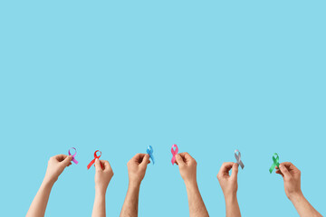 Many hands with different ribbons on blue background. Cancer awareness concept