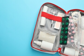 First aid kit on light blue background, top view. Space for text