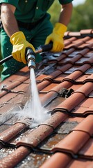 Professional roof cleaning with high pressure water jet on red ceramic tiles by a worker in safety gloves and uniform, concept of maintenance, home care, and cleanliness


