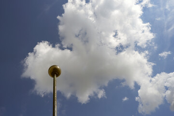 Streetlight Post Against a Blue Sky with White Clouds